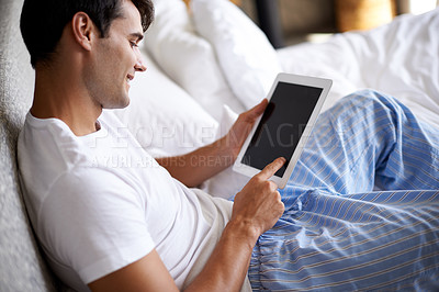 Buy stock photo Cropped shot of a handsome young man using his tablet in bed