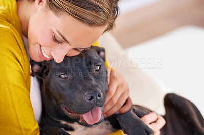 Buy stock photo Cropped shot of an attractive young woman cuddling with her dog on the sofa