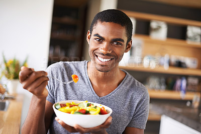 Buy stock photo Indoor shot of a gorgeous young black man showing off his fruit salad