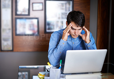 Buy stock photo A young businessman looking frustrated while sitting at his desk