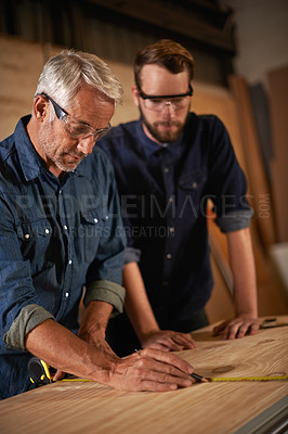 Buy stock photo Teaching, learning and carpentry apprentice with measuring tape in designer furniture manufacturing workshop. Mentorship, carpenter and young man, wood measurement and sustainable business project.