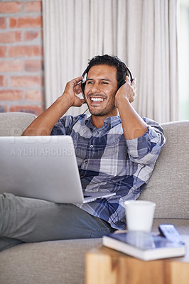 Buy stock photo Man, laptop and living room with smile, headset and internet for relax and streaming. Indian person, web and tech with house, lounge or apartment for listen to music or connectivity with subscription
