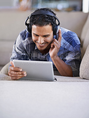 Buy stock photo A young man listening to music on his digital tablet