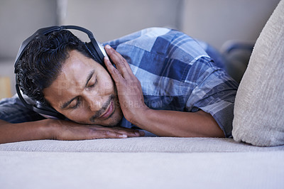Buy stock photo Man, headphones and relax with song on couch, nap and streaming radio for music or sound. Male person, home and lying on sofa for peace, comfortable and calm playlist on weekend for sleep or meditate