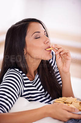 Buy stock photo Woman, cookies and eating in home on weekend, smile and satisfaction in living room for enjoyment. Female person, happy and snacks or biscuits for nutrition, relax and comfort food for wellness