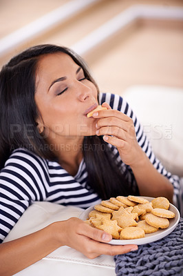 Buy stock photo Woman, cookies and eating a snack in home, smile and satisfaction in living room for enjoyment. Happy female person, lounge and couch for biscuits and nutrition, relax and comfort food for wellness 
