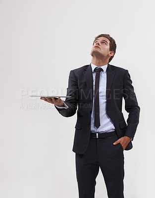 Buy stock photo Shot of a handsome young businessman holding a digital tablet looking up at copy space