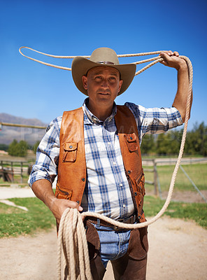 Buy stock photo Cowboy, ranch and lasso in outdoor, sun and straps for wrangler and Texas farmer at stable. Mature man, wild west and summer in agriculture, hat and male person with rope in farm job and environment