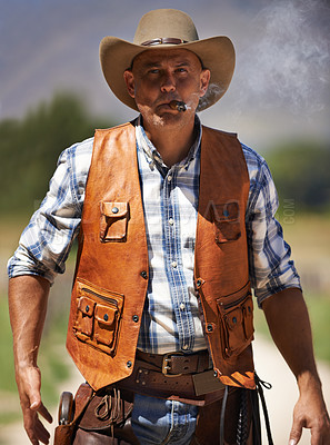 Buy stock photo A mature cowboy outdoors with his gun drawn