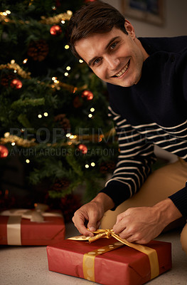Buy stock photo Portrait, Christmas tree and man wrapping present in home for preparation of holiday event of tradition. Box, gift and smile with happy young person in apartment for December celebration or vacation
