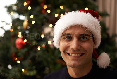Buy stock photo Portrait, house and smile on man with hat for Christmas in living room with tree for celebration. Apartment, happiness and male person with joy in family home for tradition and vacation for holiday