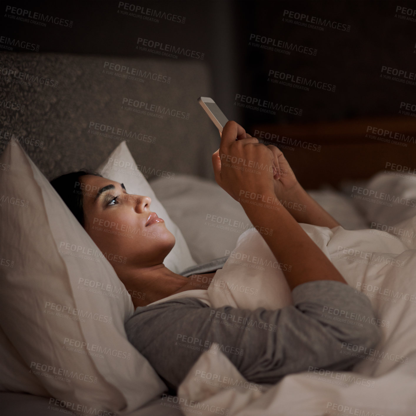 Buy stock photo A young woman sending a text message while in bed