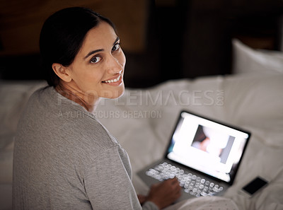 Buy stock photo A young woman working on her laptop in bed