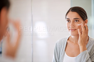 Buy stock photo Shot of a beautiful woman applying moisturizer to her face