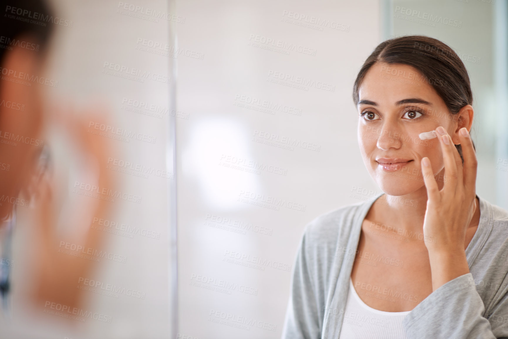 Buy stock photo Shot of a beautiful woman applying moisturizer to her face