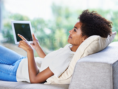 Buy stock photo Tablet, smile and relax woman on sofa, lying down and resting in home living room. Technology, touch screen and happy African woman with afro, couch and social media online for internet communication