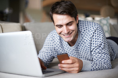 Buy stock photo Man, home and sofa on smartphone with laptop, happy and smile for social media post and entertainment. Male person, living room and couch on internet for streaming service or website for news update
