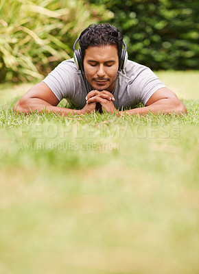 Buy stock photo Music, relax and man on grass in park, streaming sound on headphones for peace or wellness. Nature, audio or radio and happy young person lying on ground for break, rest or sleep in summer with space