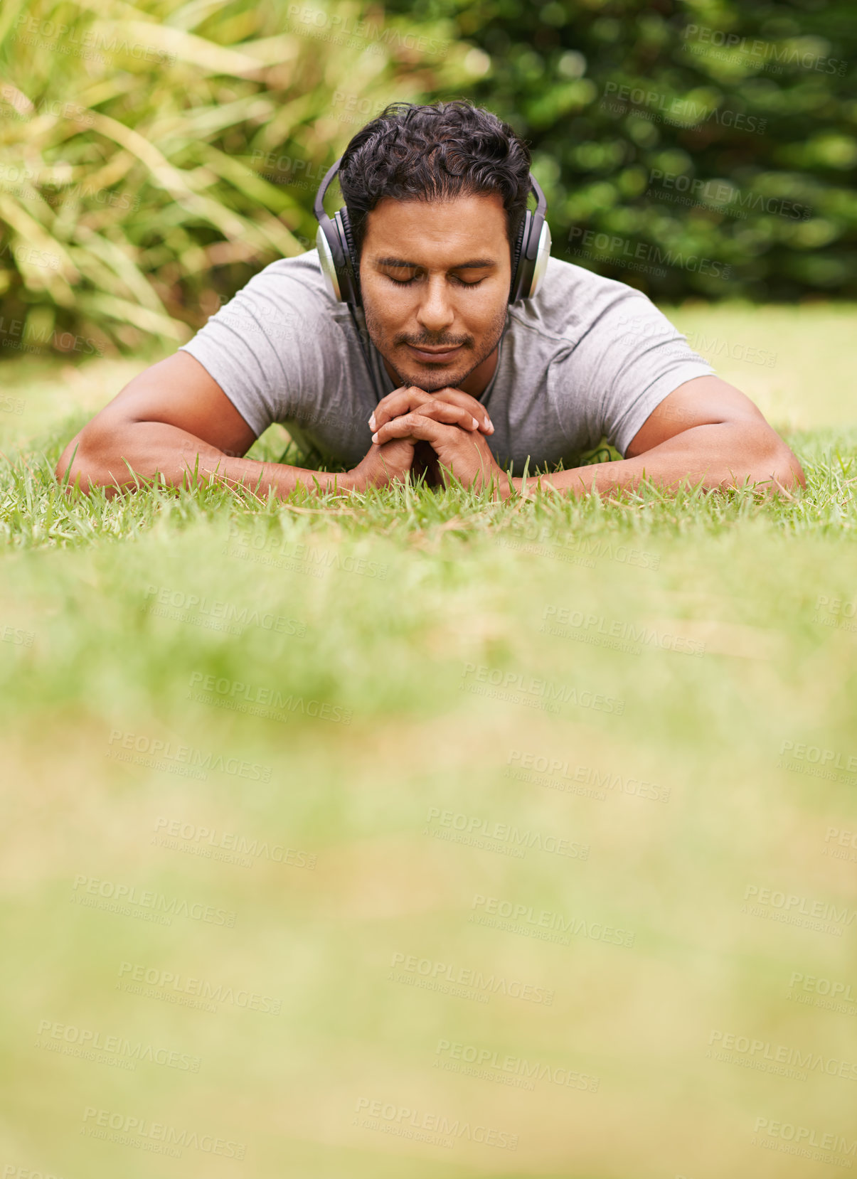 Buy stock photo Music, relax and man on grass in park, streaming sound on headphones for peace or wellness. Nature, audio or radio and happy young person lying on ground for break, rest or sleep in summer with space
