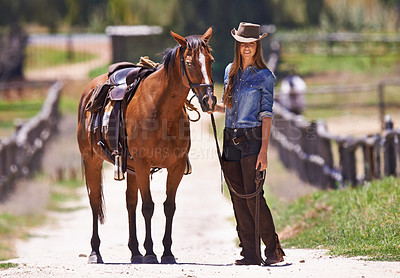 Buy stock photo Shot of a cow girl leading her horse around a ranch