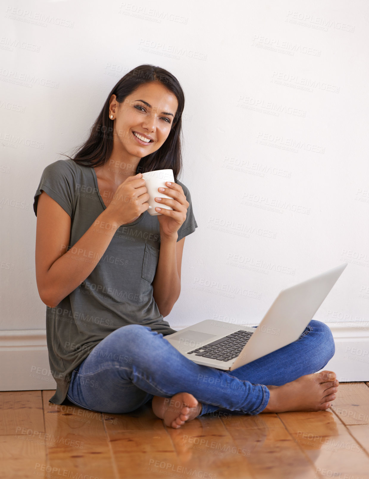 Buy stock photo Shot of a young woman sitting on the floor at home drinking a coffee and using a laptop