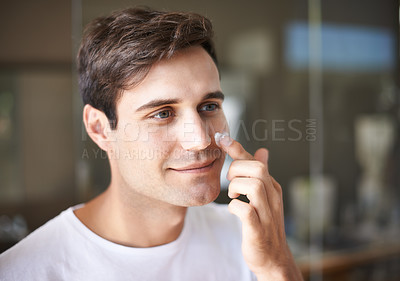 Buy stock photo Closeup of a young man applying lotion to his face