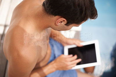 Buy stock photo Rearview shot of a man using his digital tablet while resting his feet inside of the pool