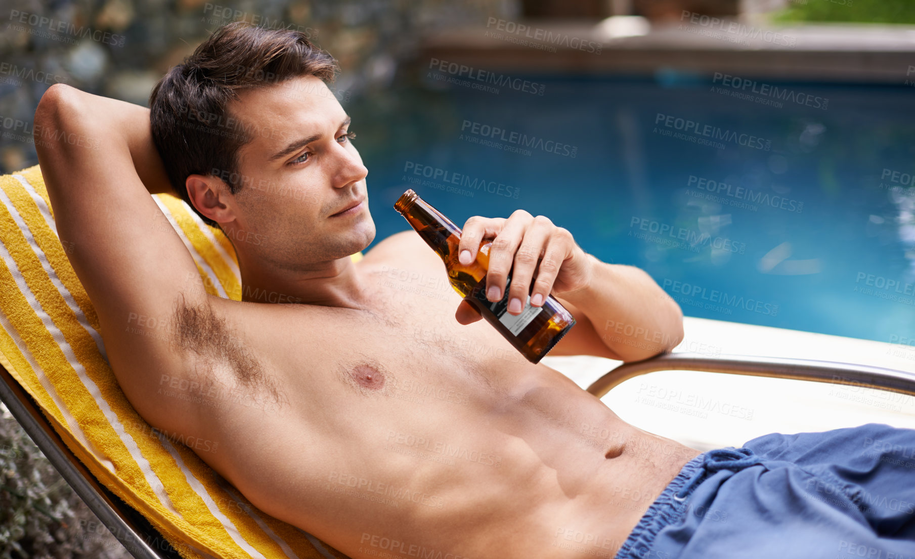 Buy stock photo Man, bed and drink by swimming pool with beer to relax or chill on summer vacation, luxury and resort or villa. Male person, bottle and alcohol for refreshments on tropical holiday in Maldives.