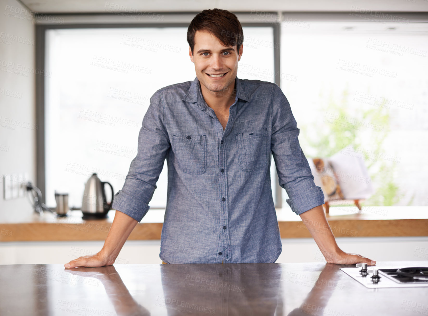 Buy stock photo Portrait of a handsome young man standing behind his kitchen countertop