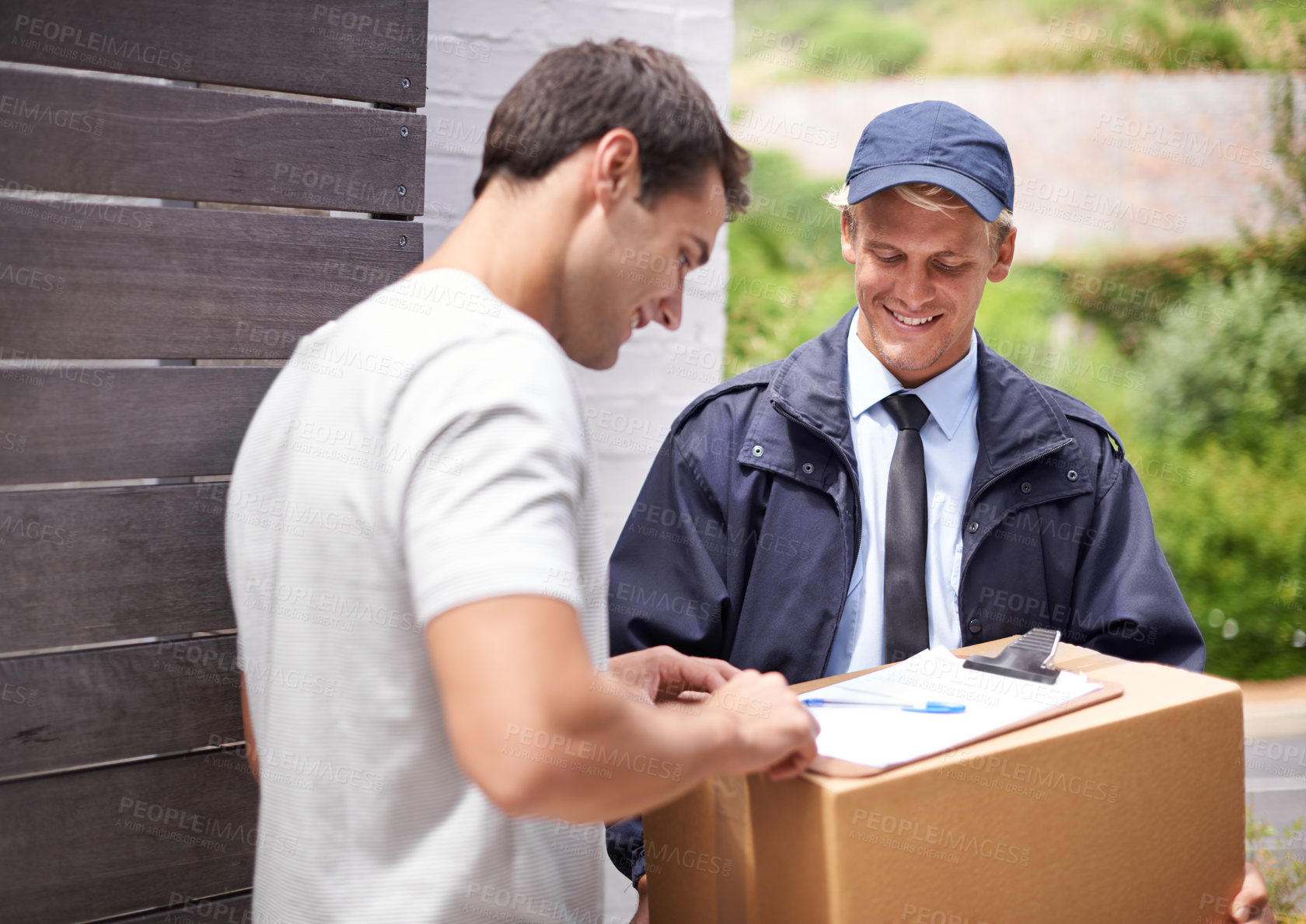 Buy stock photo Shot of a young man receiving a parcel from the delivery man