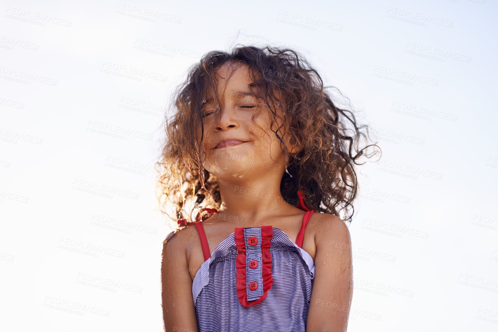 Buy stock photo Child, girl and water with face, costume and blue summer sky for relax and smile. Kid, youth and sunshine with happiness, outdoor and play with curly hair and fun for sunny positivity and childhood