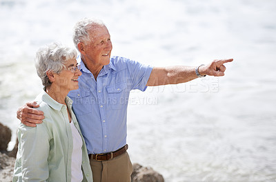 Buy stock photo Senior, couple and point at beach with smile for retirement vacation or anniversary to relax with love, view and commitment with support. Elderly man, woman and together by ocean for peace on holiday