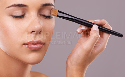 Buy stock photo Face, hand and brush for eyeshadow with woman in studio, makeup and beauty with application on purple background. Cosmetology, transformation and cosmetic care with tools, powder product and shine