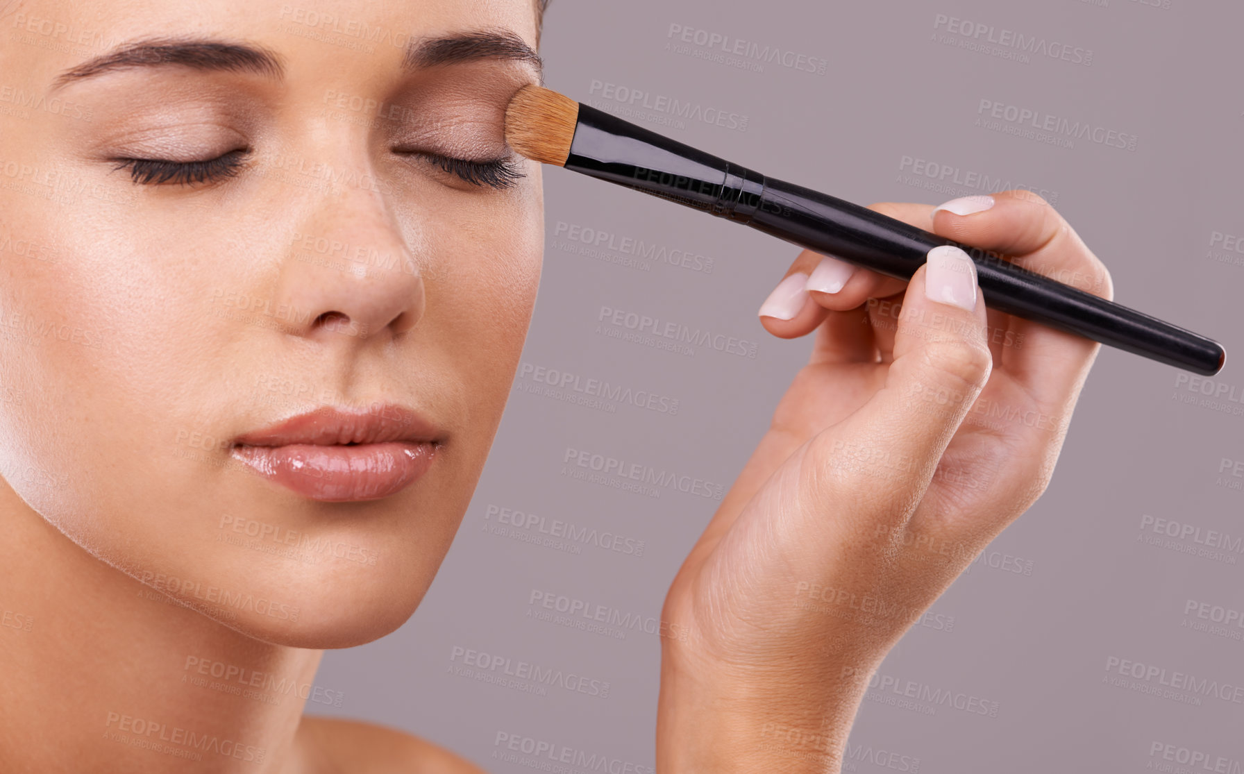 Buy stock photo Face, hand and brush for eyeshadow with woman in studio, makeup and beauty with application on purple background. Cosmetology, transformation and cosmetic care with tools, powder product and shine