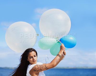 Buy stock photo Cropped shot of a gorgeous tattooed young woman holding balloons