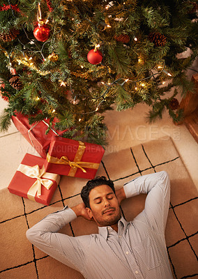 Buy stock photo Shot of a young man napping under the christmas tree
