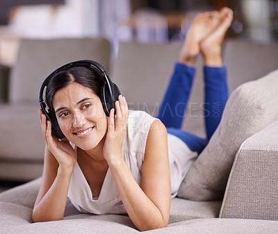 Buy stock photo Happy woman, headphones and listening to music with smile on sofa for free time, comfort or relaxing at home. Female lying on living room couch with headset for audio sound track or relax on holiday