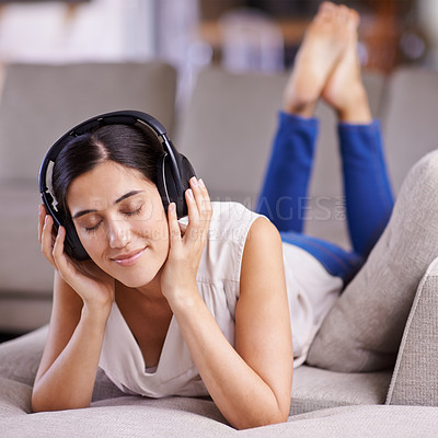 Buy stock photo Shot of a young woman listening to music while relaxing at home