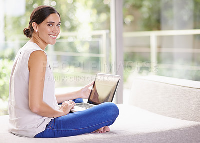 Buy stock photo Shot of an attractive young woman using a laptop while relaxing at home