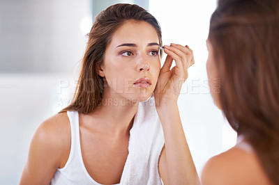 Buy stock photo A young woman tweezing her eyebrows in front of a mirror