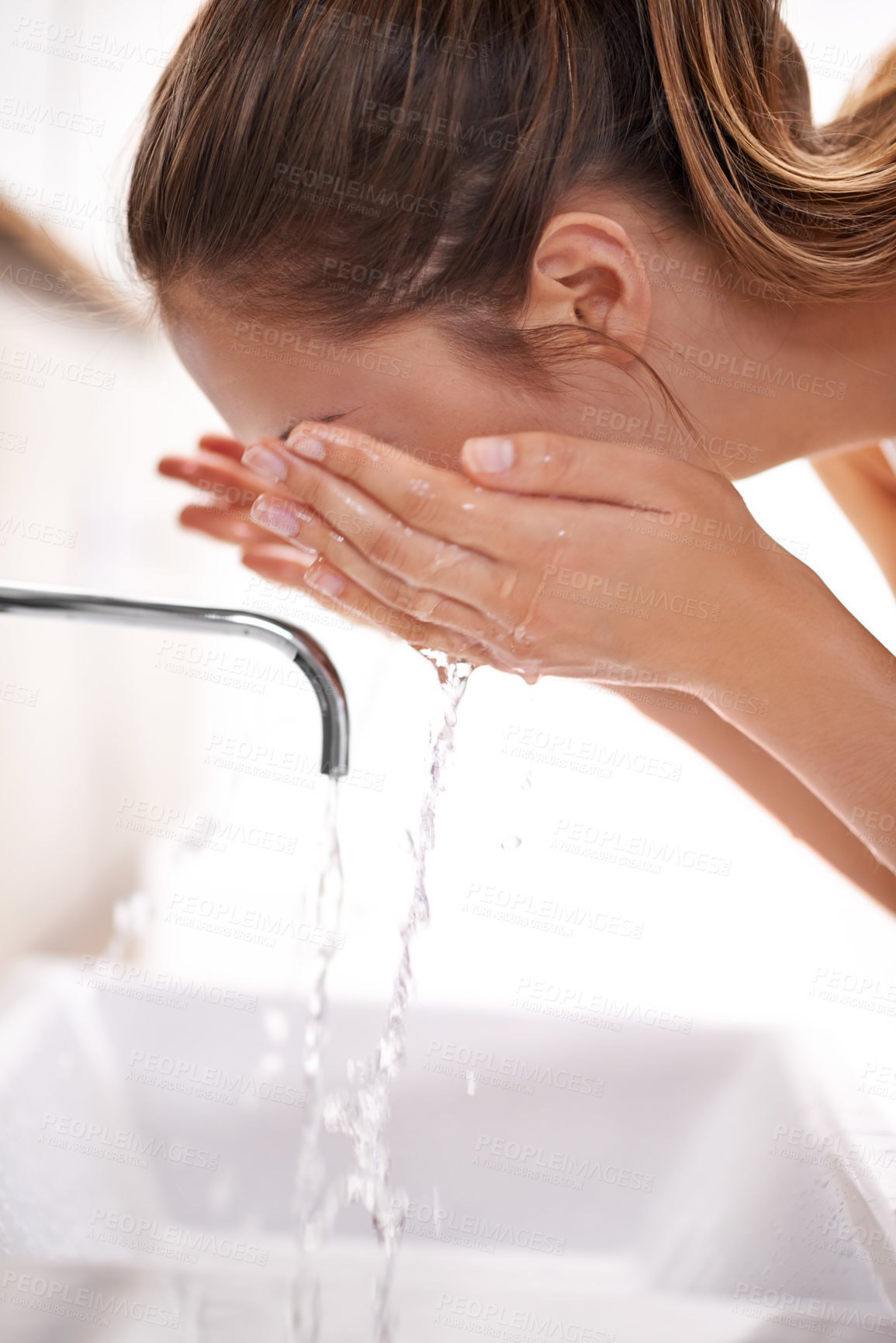 Buy stock photo Closeup shot of a young woman washing her face over a sink