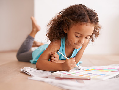 Buy stock photo Shot of a little girl lying on the floor and painting a picture