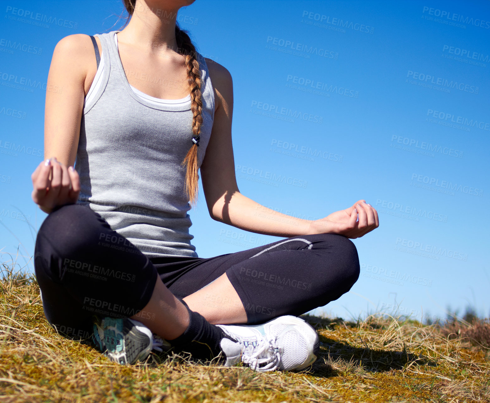 Buy stock photo Cropped shot of a young woman meditating outdoors in sports gear