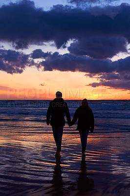 Buy stock photo Silhouette of a couple going for a walk on the beach at sunset
