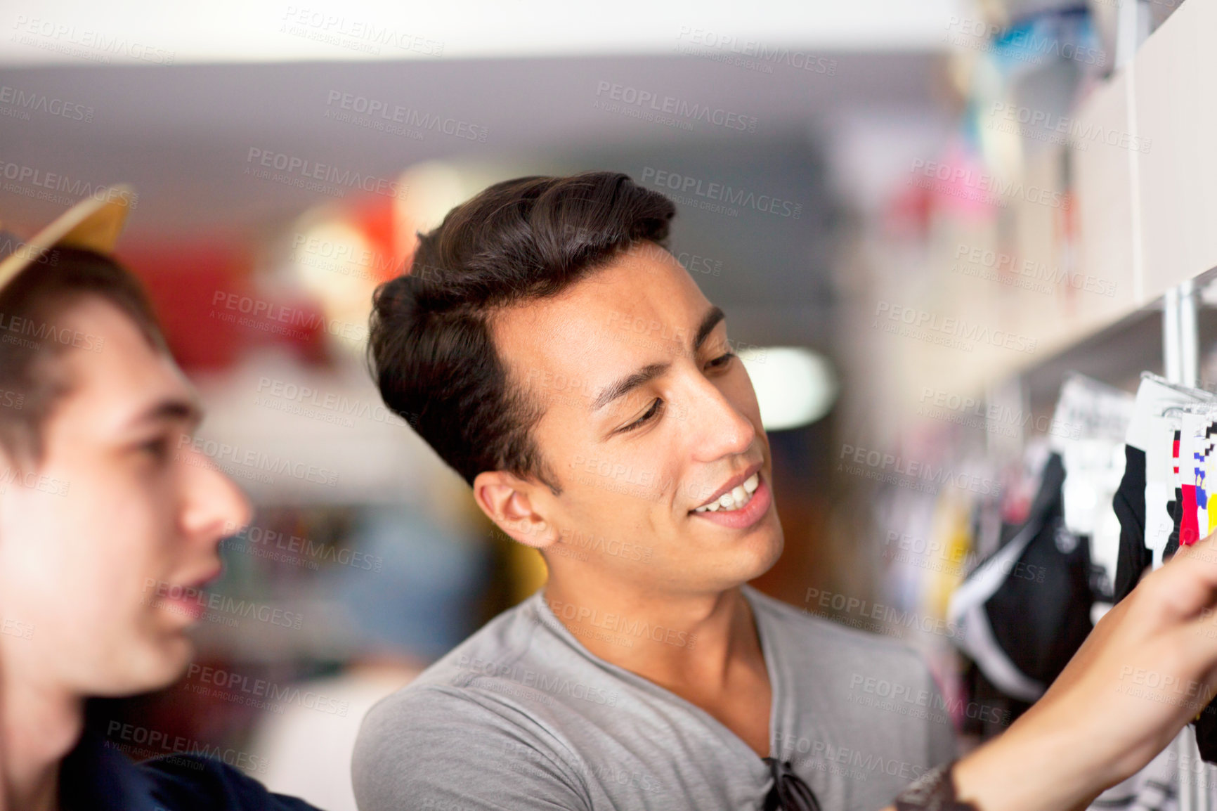 Buy stock photo Closeup of two young men doing shopping in a retail store. Gay couple browsing in a store for clothing during a shopping spree on the weekend. Friends looking to purchase some fashionable items 