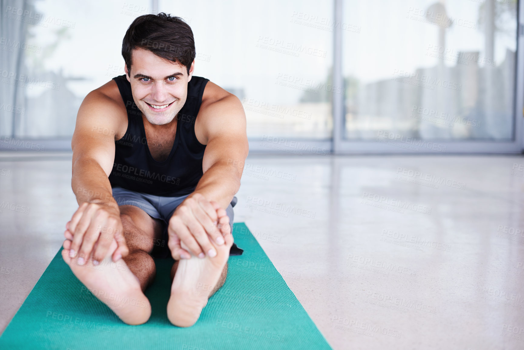 Buy stock photo A portrait of a happy young man stretching on an exercise mat at home