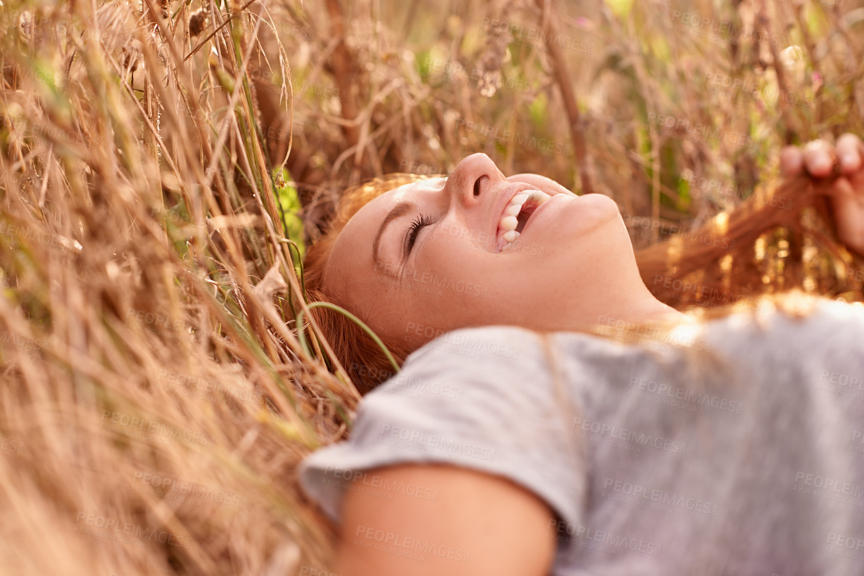 Buy stock photo Happy woman, laughing and relax with wheat field in nature for funny summer, weekend or outdoor break. Face of female person or ginger lying on grass with smile and enjoying fresh air in countryside