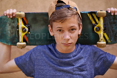 Buy stock photo Portrait of a teenage boy holding his skateboard while standing  against a wall