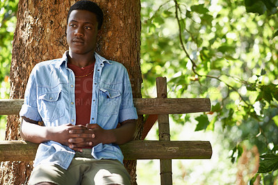 Buy stock photo Teen, boy and thinking by tree outdoors, bench and relax in woods or forest on summer holiday. Black male person, nature and ponder or wonder in park or garden, calm and peace on travel to Nigeria