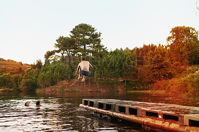 Buy stock photo Lake, pier and person jump in water on vacation in summer or holiday in nature with adventure. Excited, energy and man enjoy river on deck with freedom or people swimming outdoor in dam for fun